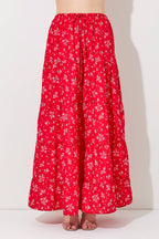 Woman wearing a floral print tiered red skirt against a gray background