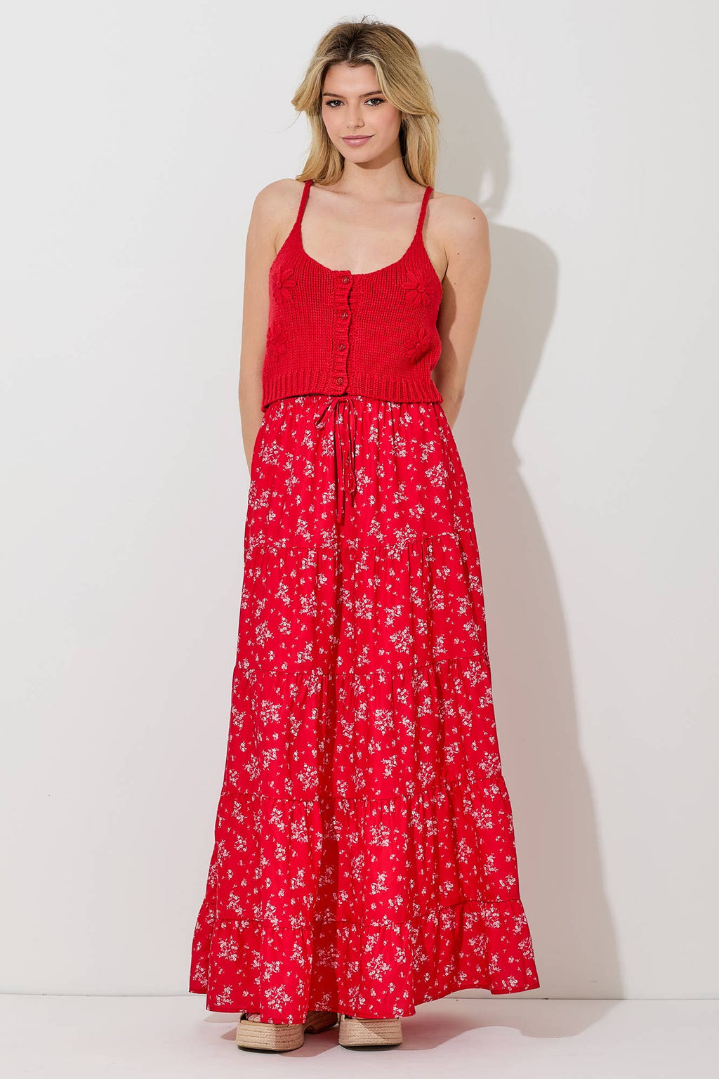 Woman wearing a floral print tiered red skirt and red top against a gray background