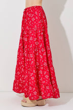 Woman wearing a floral print tiered red skirt against a gray background