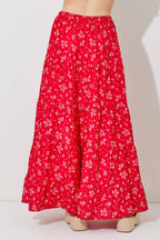 Woman wearing a floral print tiered red skirt against a gray background