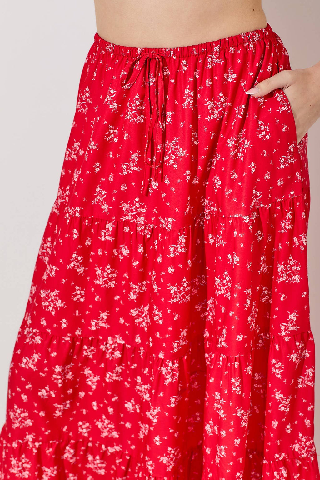Woman wearing a floral print tiered red skirt against a gray background