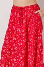 Woman wearing a floral print tiered red skirt against a gray background