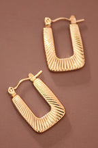 Textured gold hoop earrings on a brown background