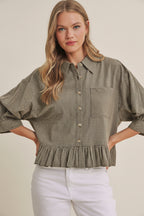 Woman wearing an olive micro check blouse with puff sleeves and ruffle hem on a beige background