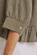 Close-up of a checkered shirt with a button on a white background