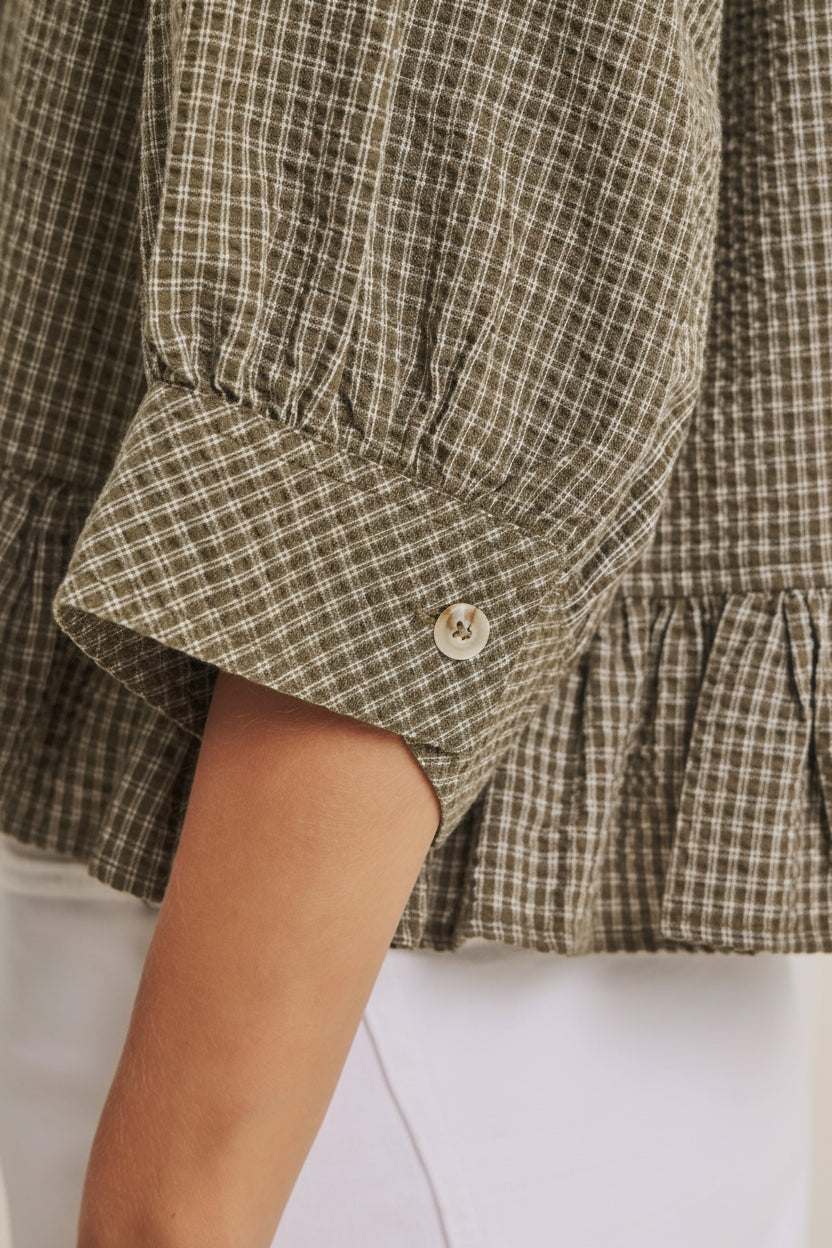 Close-up of a checkered shirt with a button on a white background