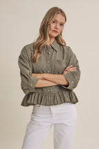 Woman wearing an olive micro check blouse with puff sleeves and ruffle hem on a beige background