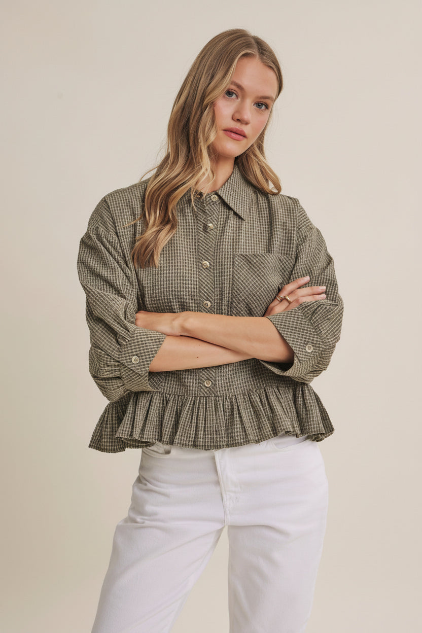 Woman wearing an olive micro check blouse with puff sleeves and ruffle hem on a beige background