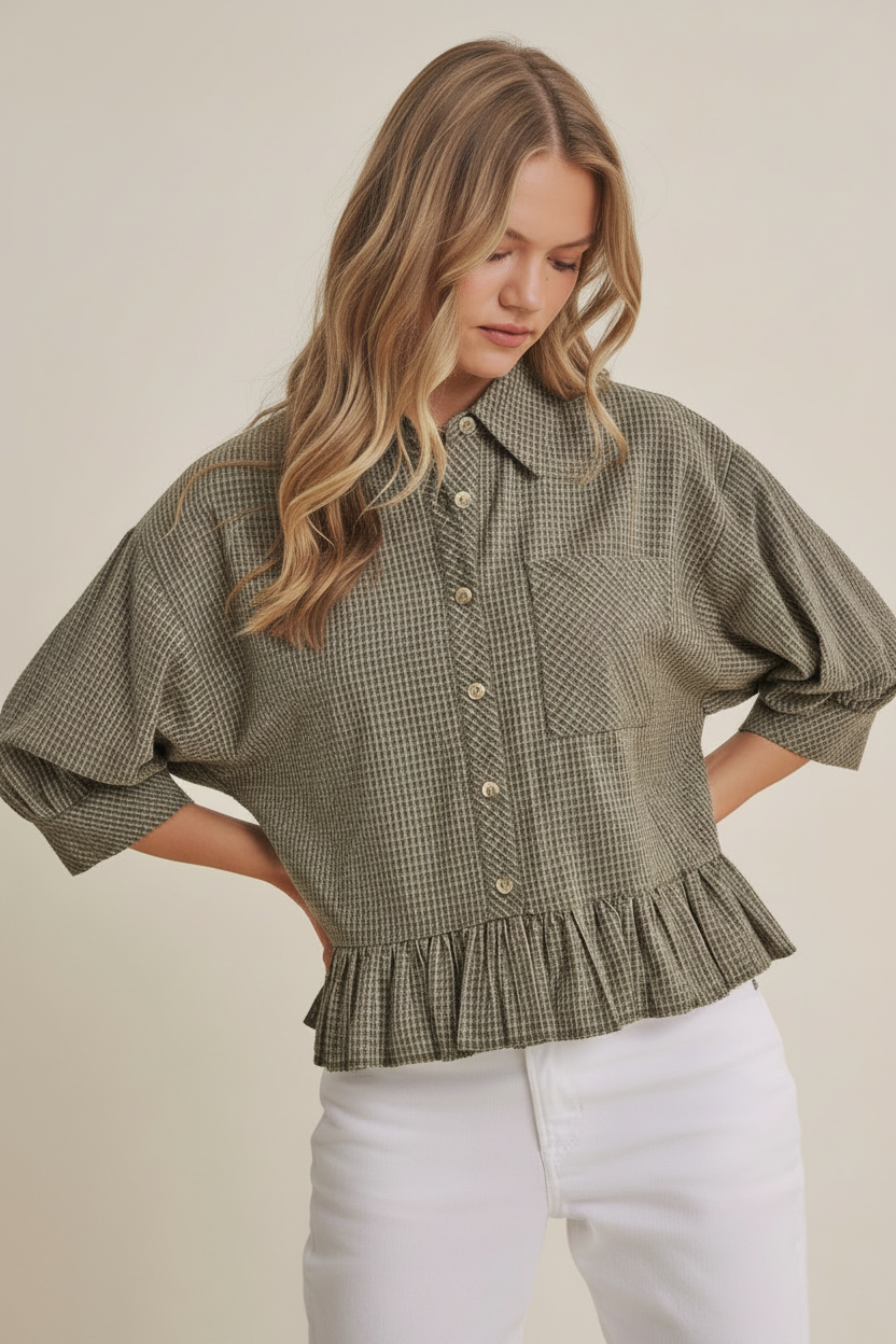 Woman wearing an olive micro check blouse with puff sleeves and ruffle hem on a beige background