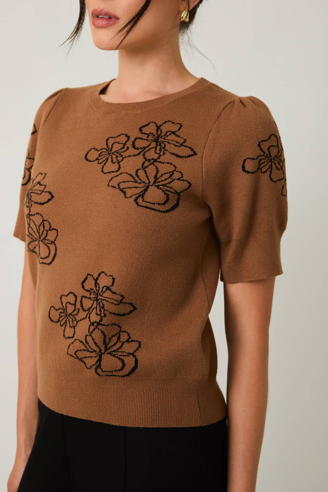 Brown sweater with flower design on a neutral background