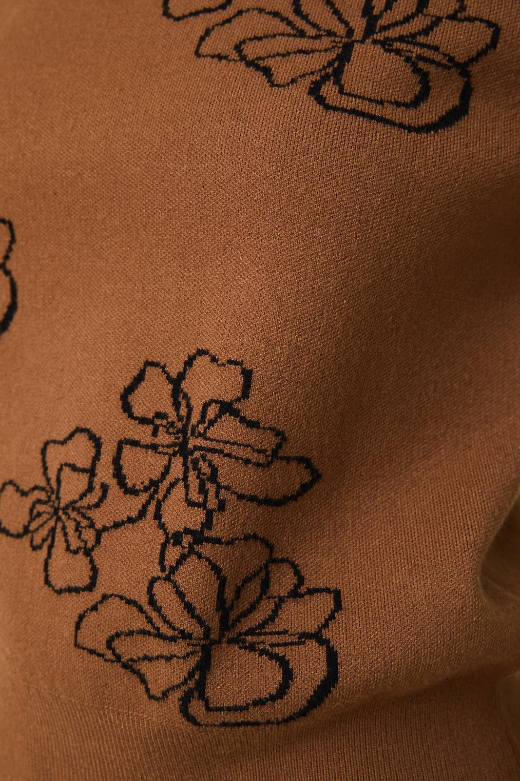 Close-up of brown sweater knit with black flowers knitted in