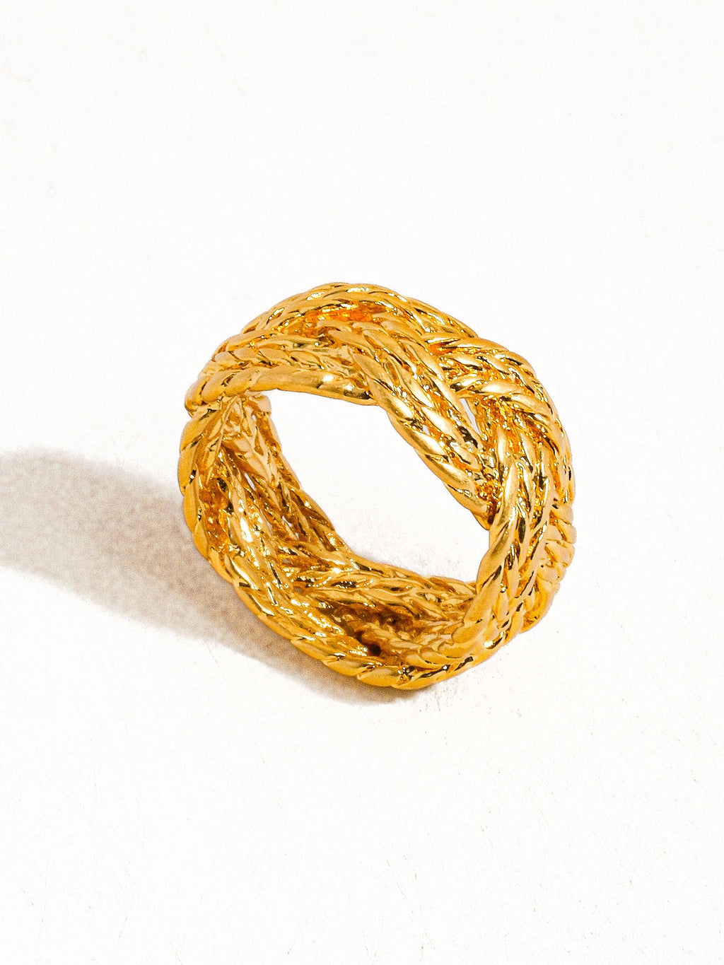 Gold ring with braided design on a white background