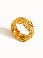 Gold ring with braided design on a white background