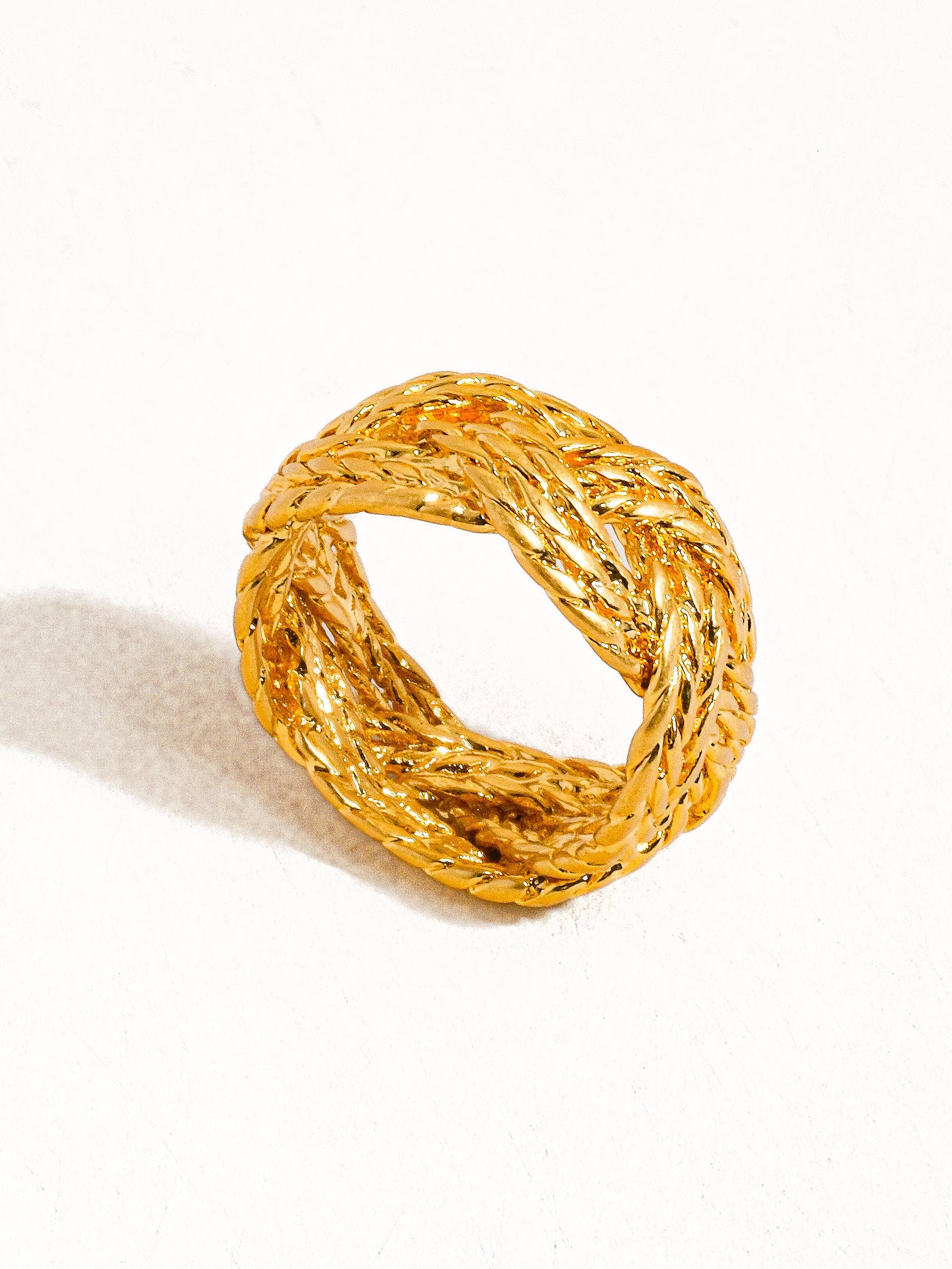 Gold ring with braided design on a white background