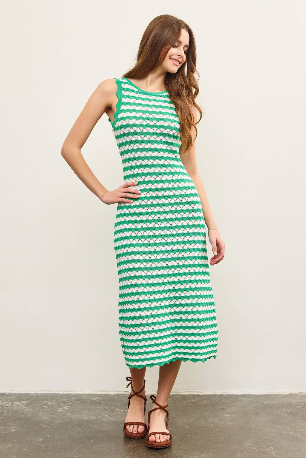 Woman wearing a green and white wavy striped tank midi dress against a plain background