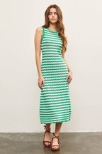Woman wearing a green and white wavy striped tank midi dress against a plain background