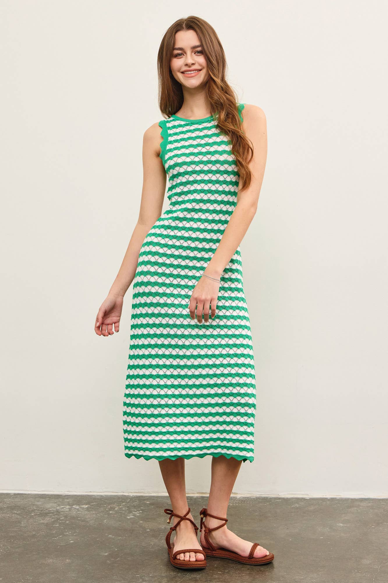 Woman wearing a green and white wavy striped tank midi dress against a plain background