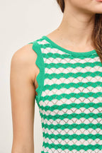 Woman wearing a green and white wavy striped tank midi dress with scalloped tank edge against a plain background