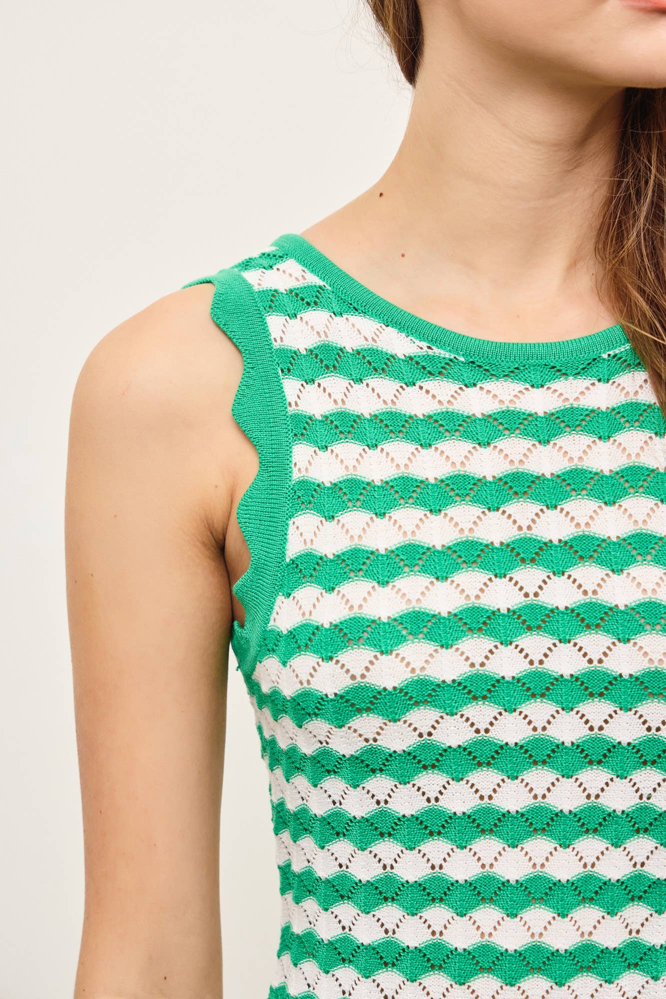 Woman wearing a green and white wavy striped tank midi dress with scalloped tank edge against a plain background