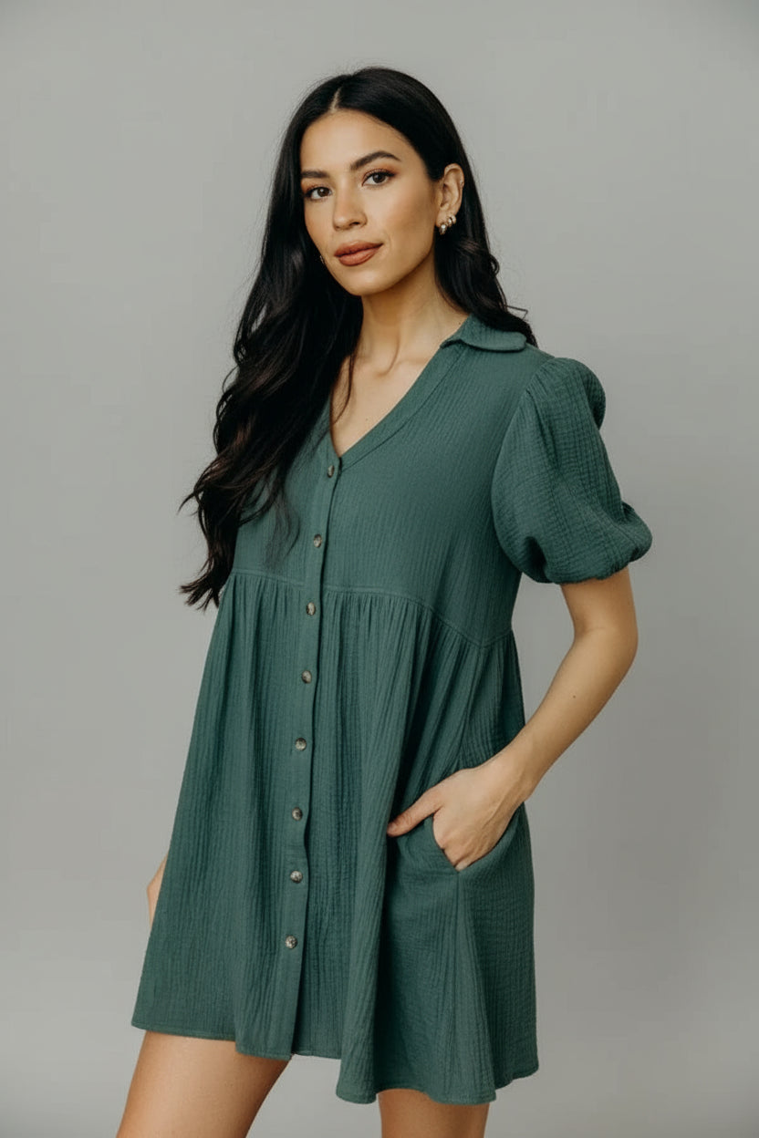 Woman wearing a green bubble sleeve dress with buttons in an indoor setting