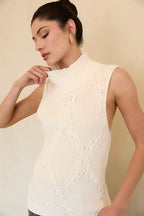 Woman wearing a cream mock neck knitted sleeveless top against a beige background