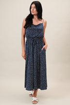 Woman wearing a navy dress with ivory polka dots on a beige background