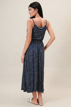 Woman wearing a navy dress with ivory polka dots on a beige background