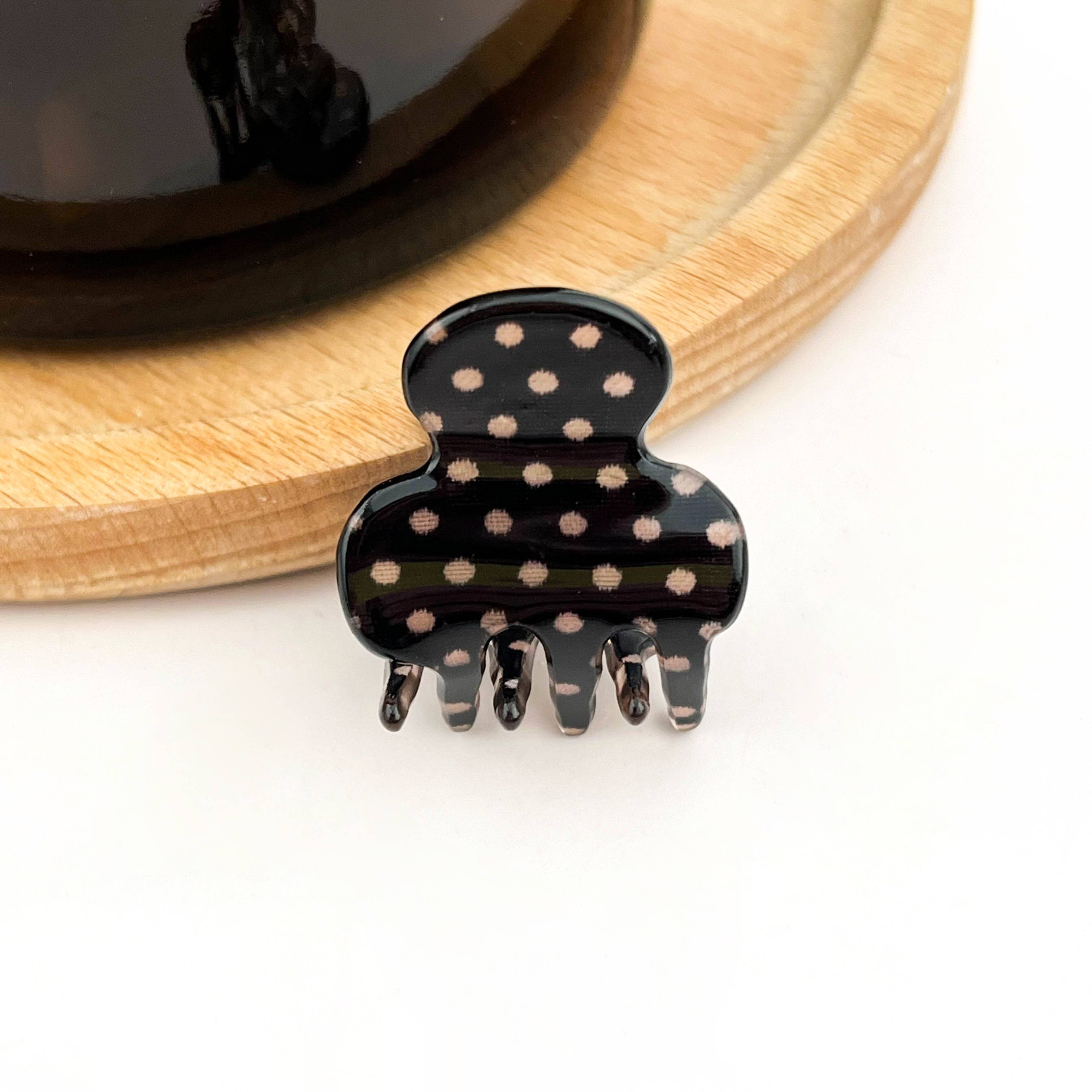 Black hair clip with tan polka dots on a white background