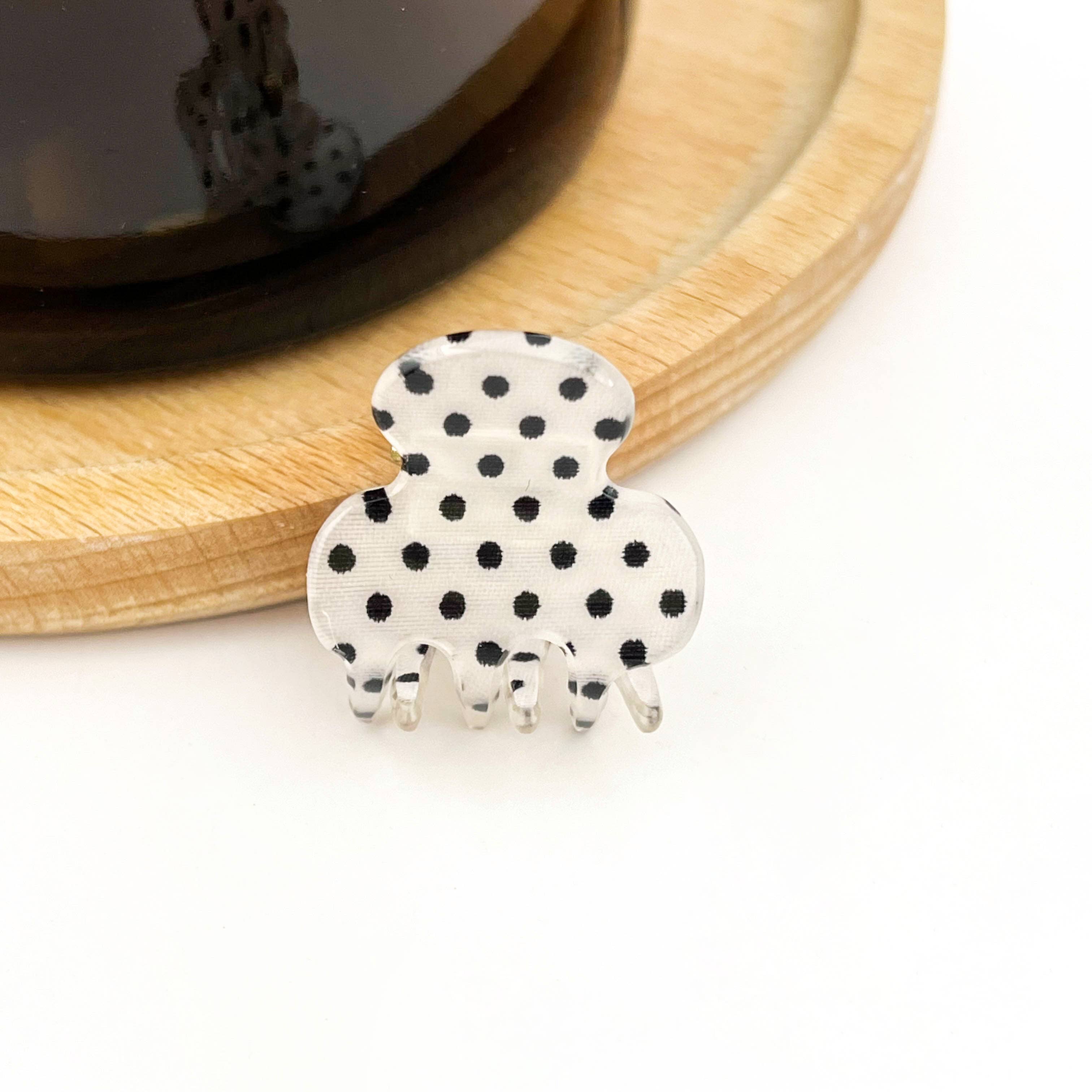 White hair clip witth black polka dots on a white background