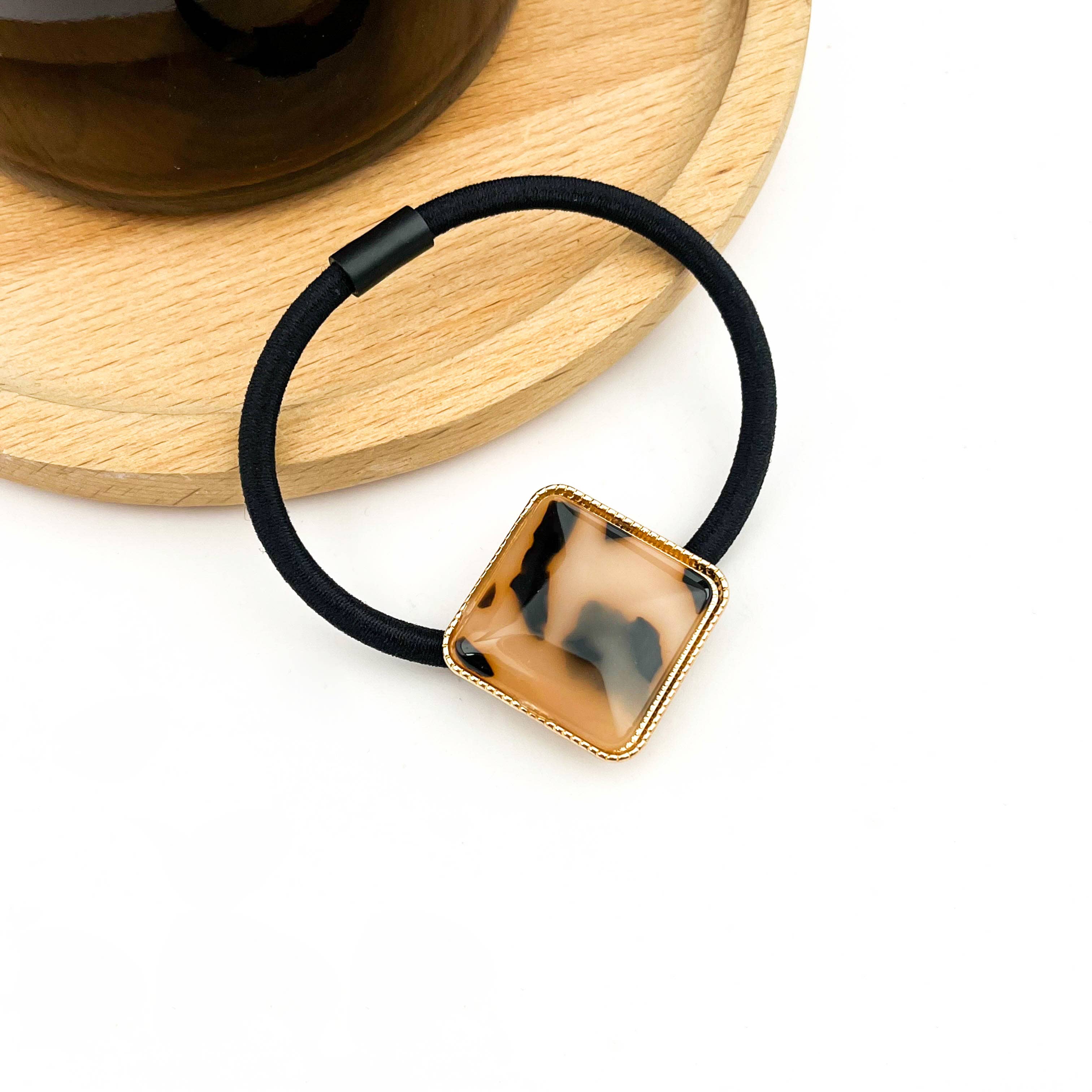 Black hair elastic with a square tortoiseshell design on a white background