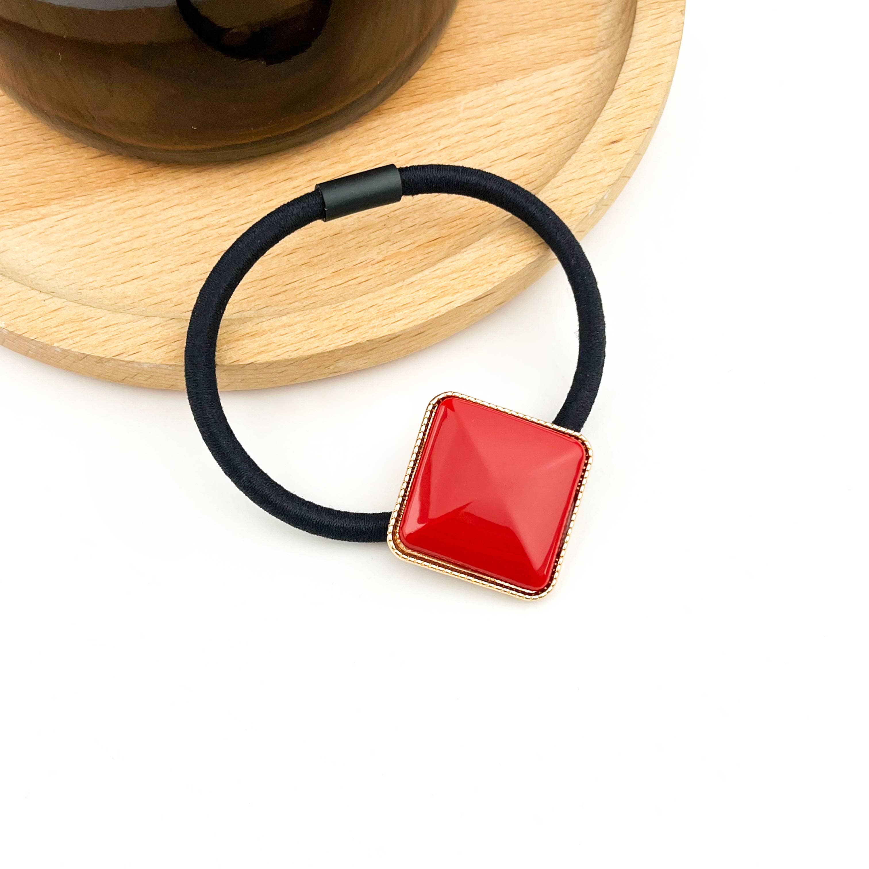 Black hair tie with a red square on a white background