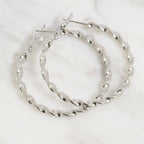 Pair of silver twisted hoop earrings on a white background