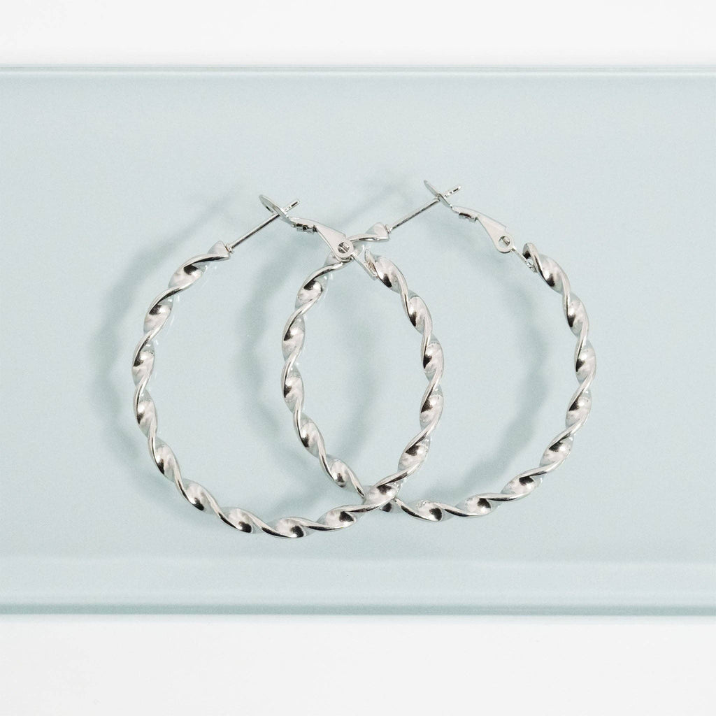 Silver twisted hoop earrings on a light blue background