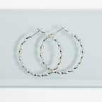 Silver twisted hoop earrings on a light blue background