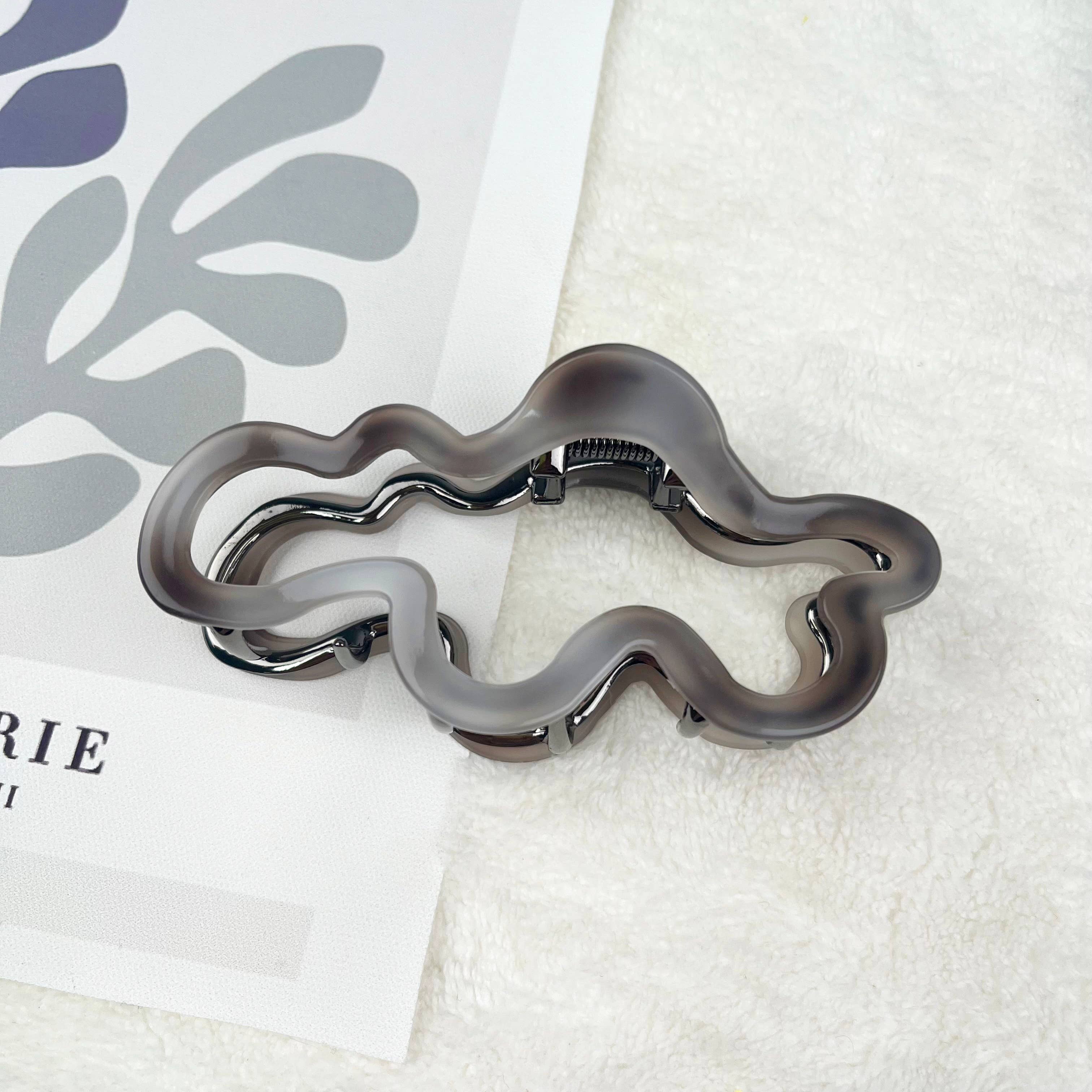 Cloud design hair claw clip on a textured white surface with a leaf design in the background