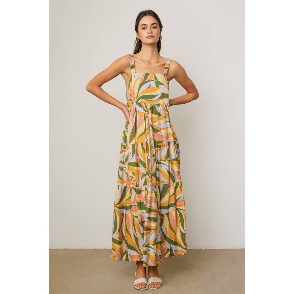 Woman wearing a colorful tropical design maxi dress against a neutral background