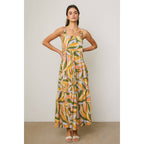 Woman wearing a colorful tropical design maxi dress against a neutral background