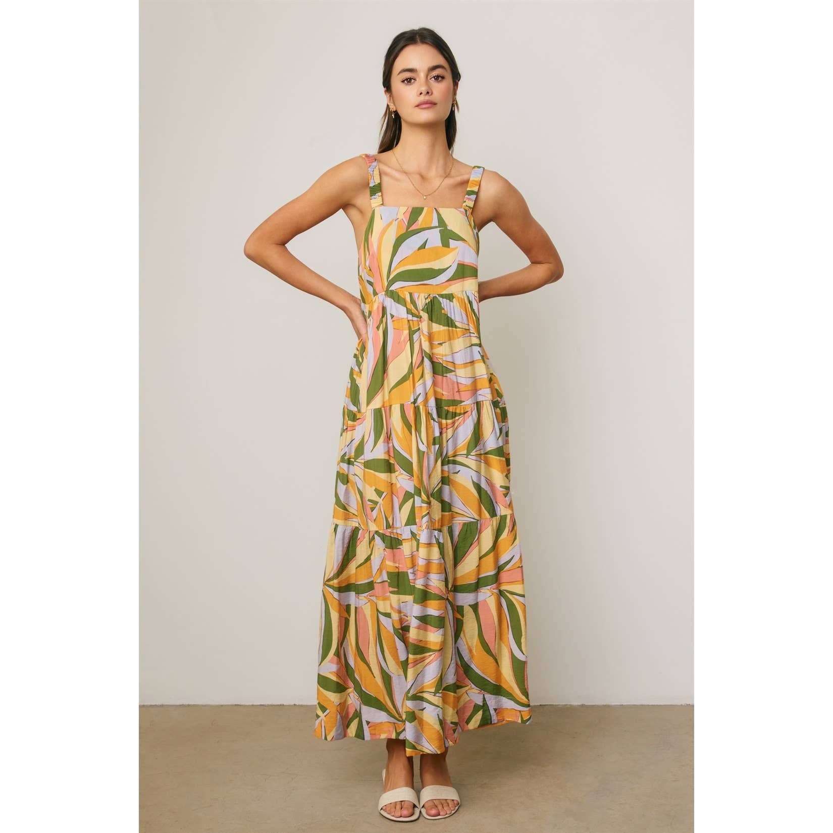 Woman wearing a colorful tropical design maxi dress against a neutral background