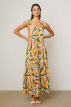 Woman wearing a colorful tropical design maxi dress against a neutral background