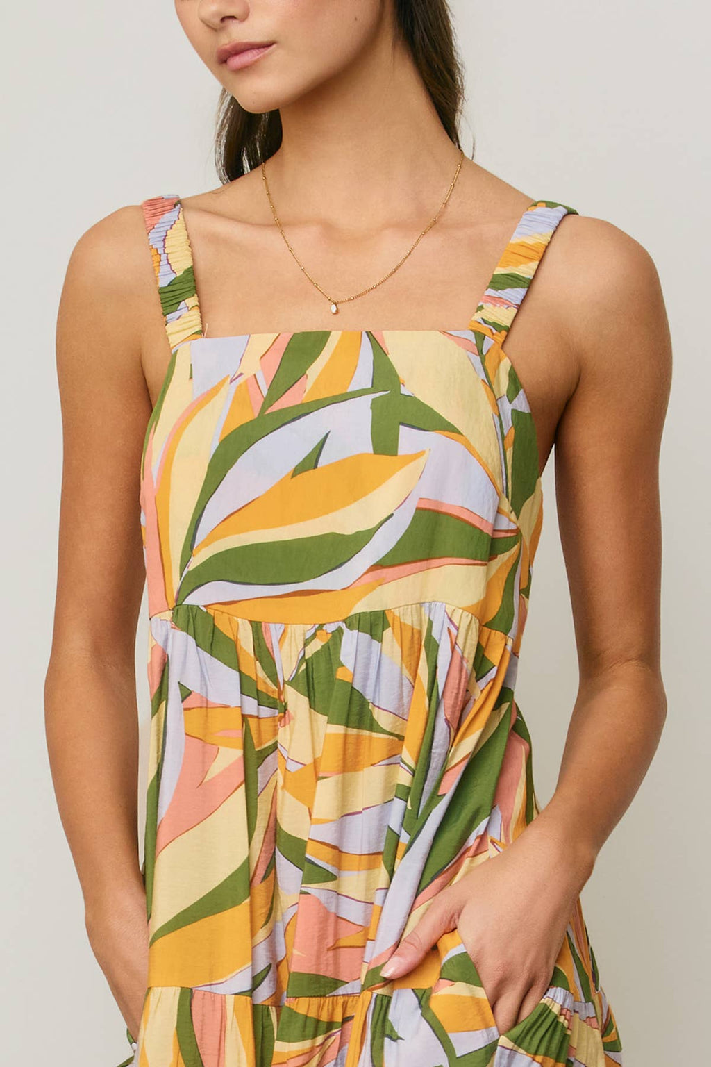 Woman wearing a colorful tropical design maxi dress against a neutral background
