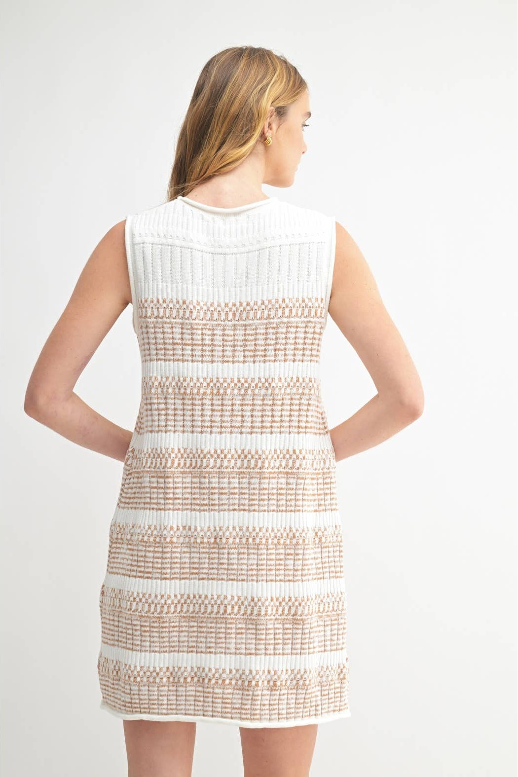 Back view of a woman wearing a striped ivory and brown textured knit sweater dress against a white background 