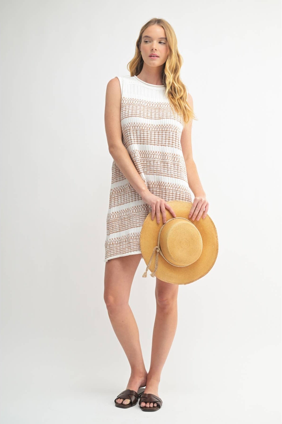 Woman wearing a striped ivory and brown textured knit sweater dress against a white background 