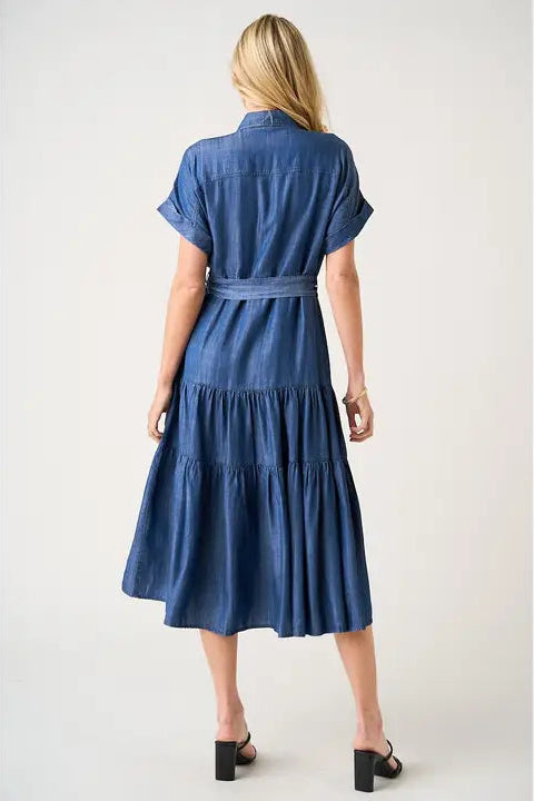Back view of a woman wearing a blue denim dress on a white background
