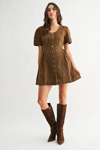 Woman wearing a leopard print dress with brown knee-high boots on a white background