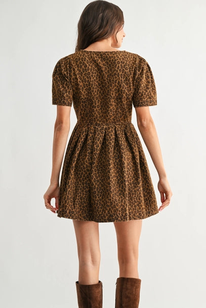 Back view of a woman wearing a leopard print dress with brown boots on a white background
