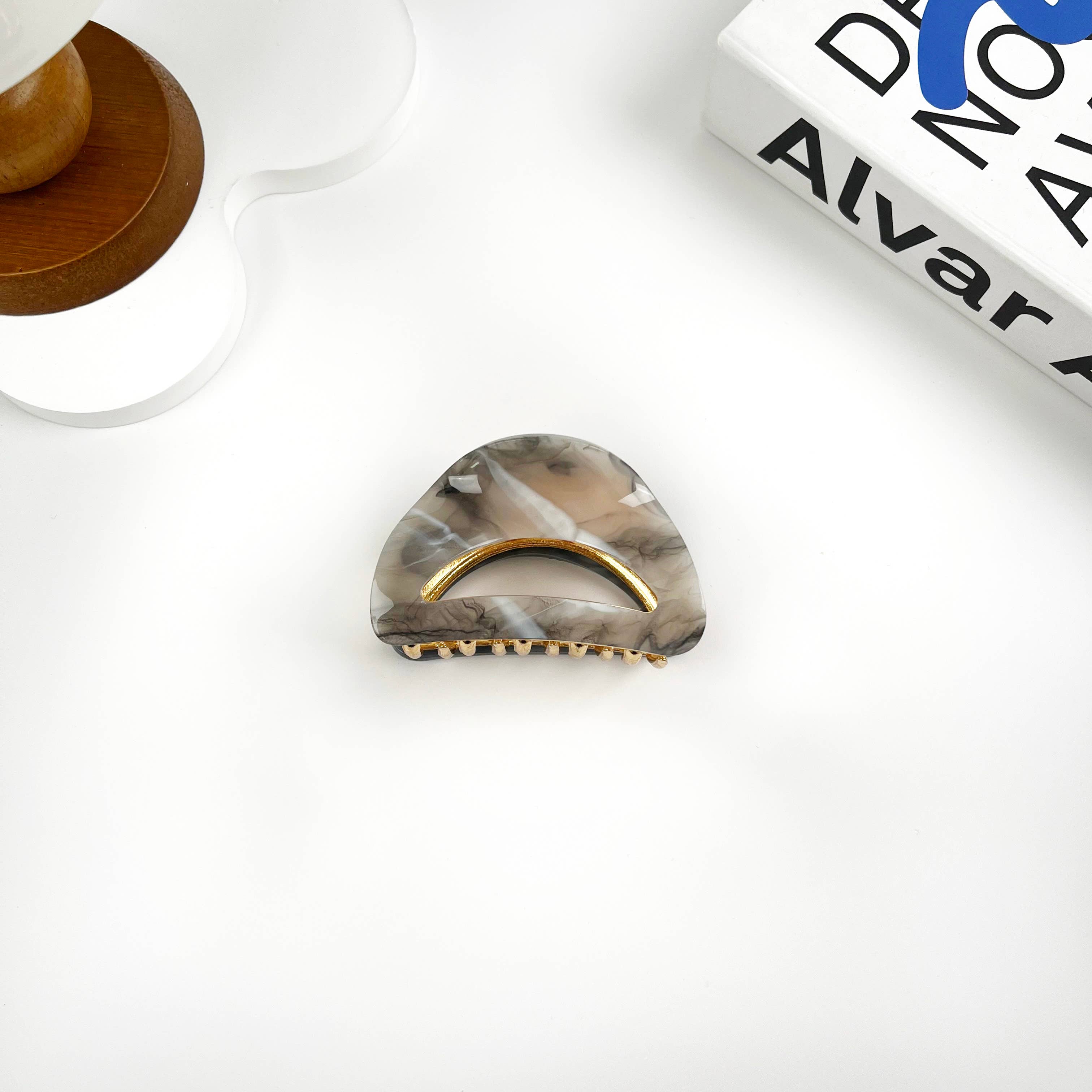 Gray hair claw clip with gold accents on a white surface