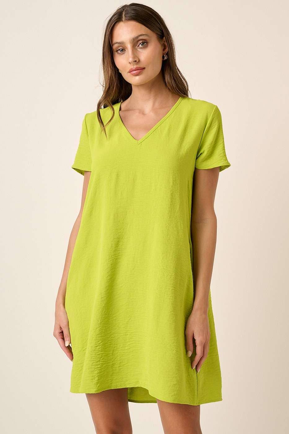 Woman wearing a lime green shift dress against a beige background