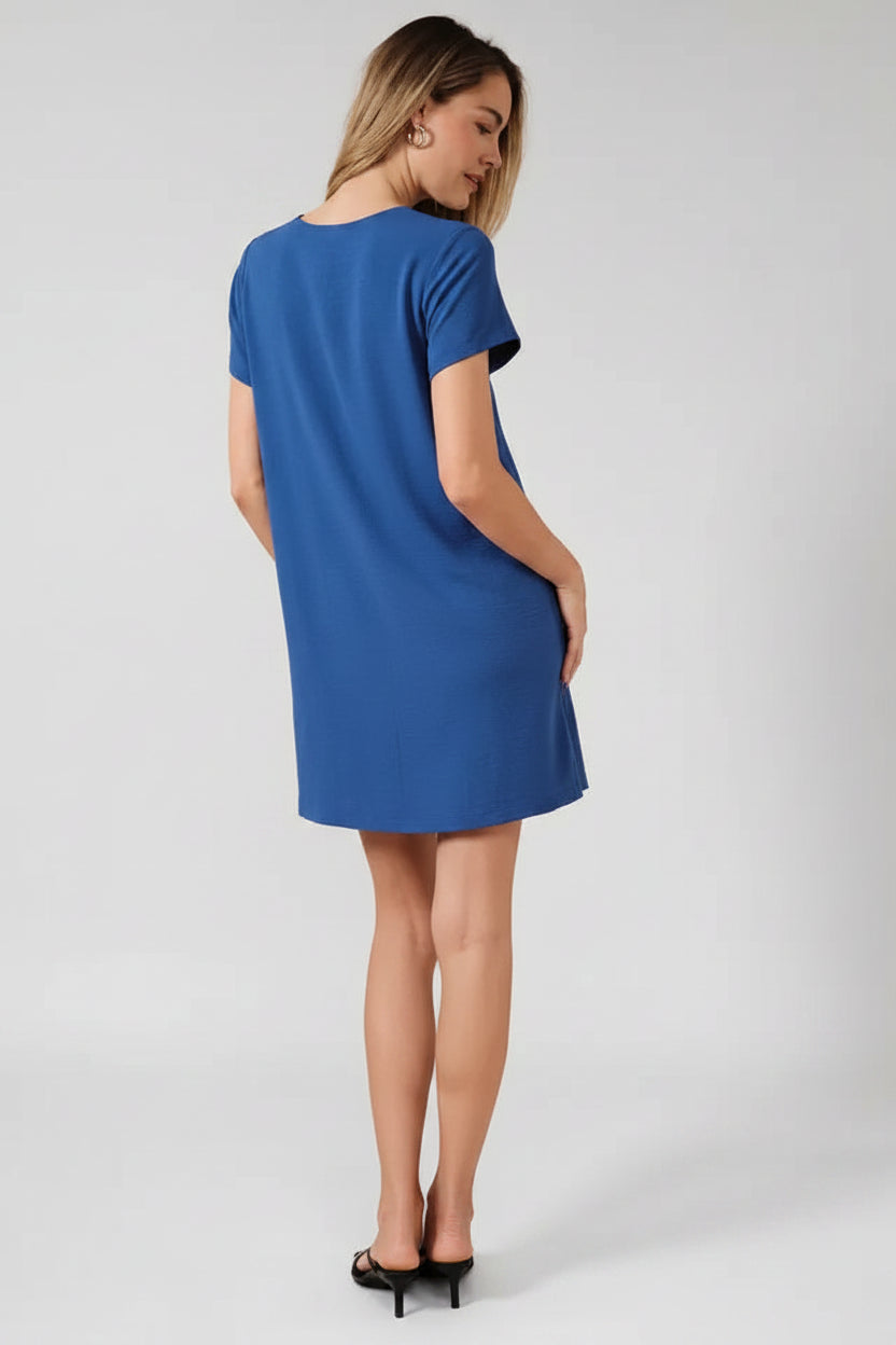Back voew of a woman wearing a royal blue dress against a beige background