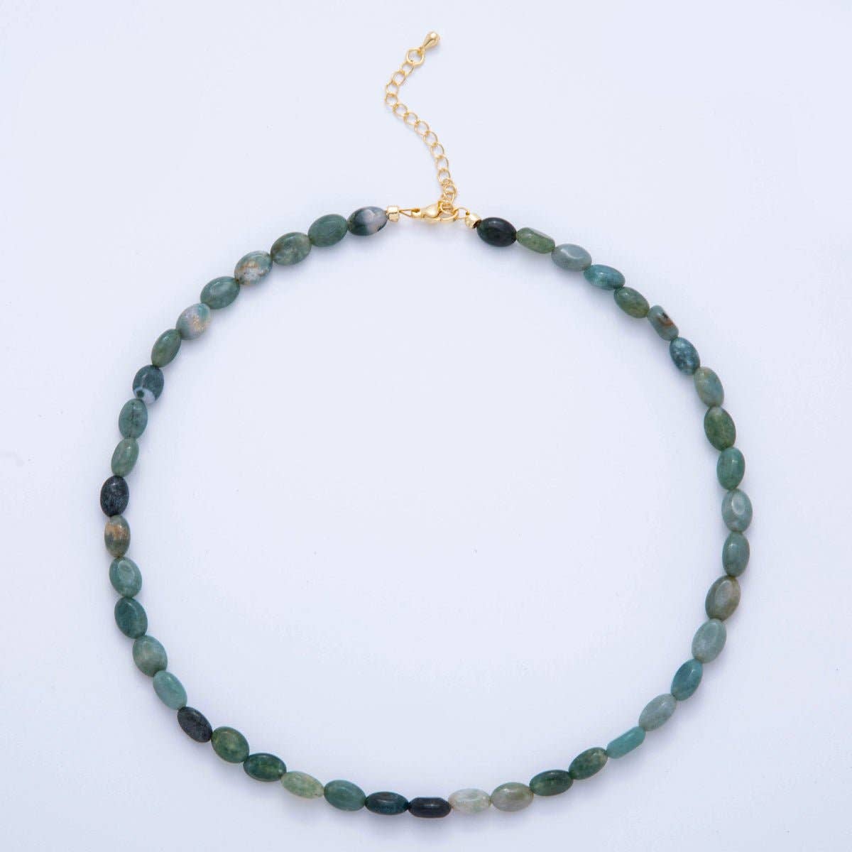 A beaded choker necklace made of small oval green beads with a gold-tone chain extender clasp, displayed on a plain white background.