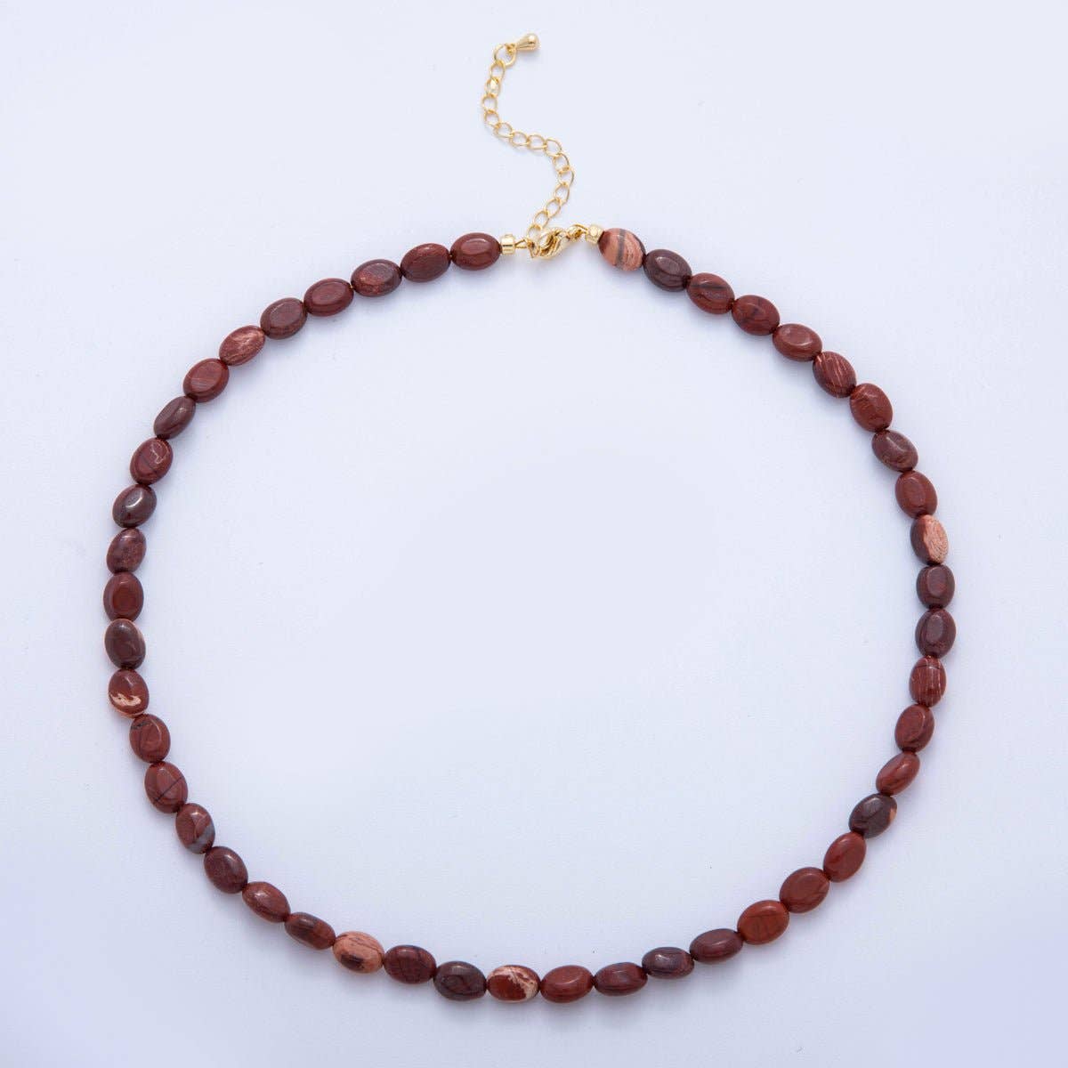 Beaded necklace with gold clasp on a light purple background